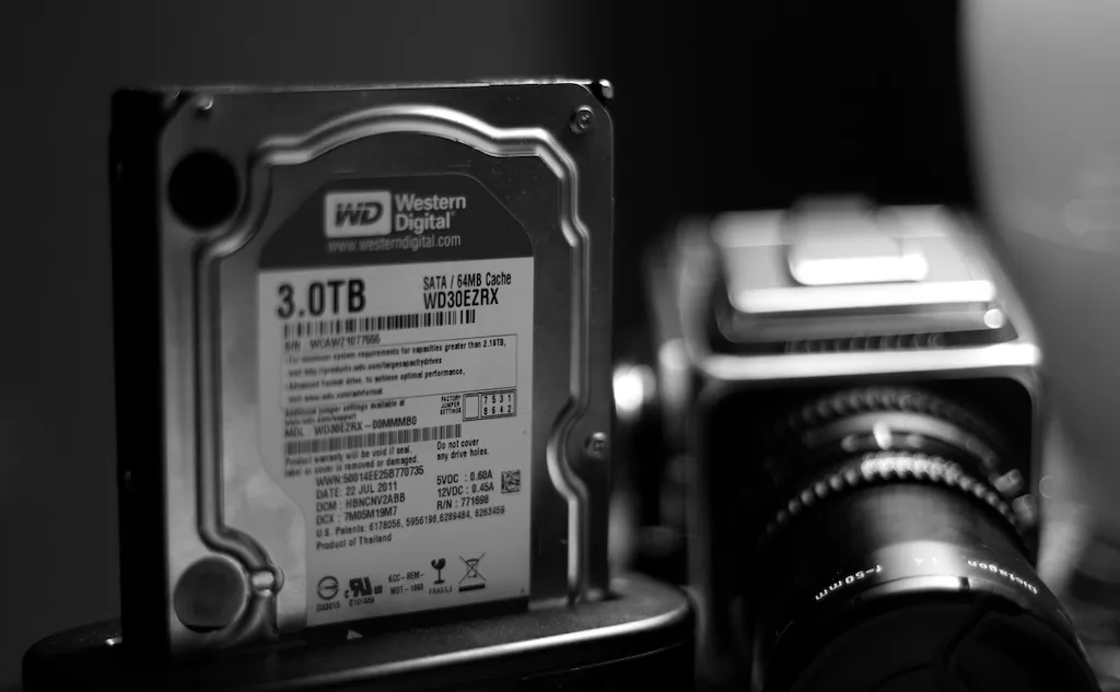 Black-and-white photograph of a 3 TB hard drive next to a medium-format camera